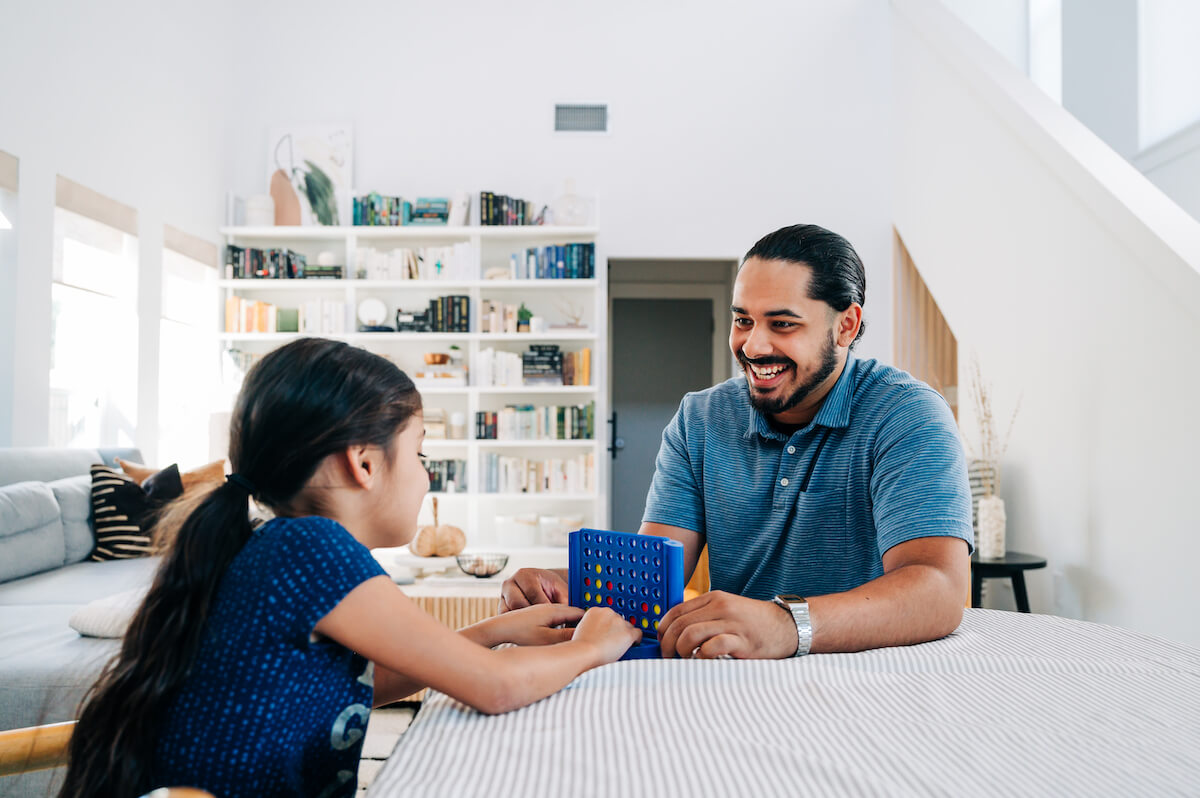 A dentist plays a game with his daughter in their home. For a dentist, work-life balance is incredibly important.