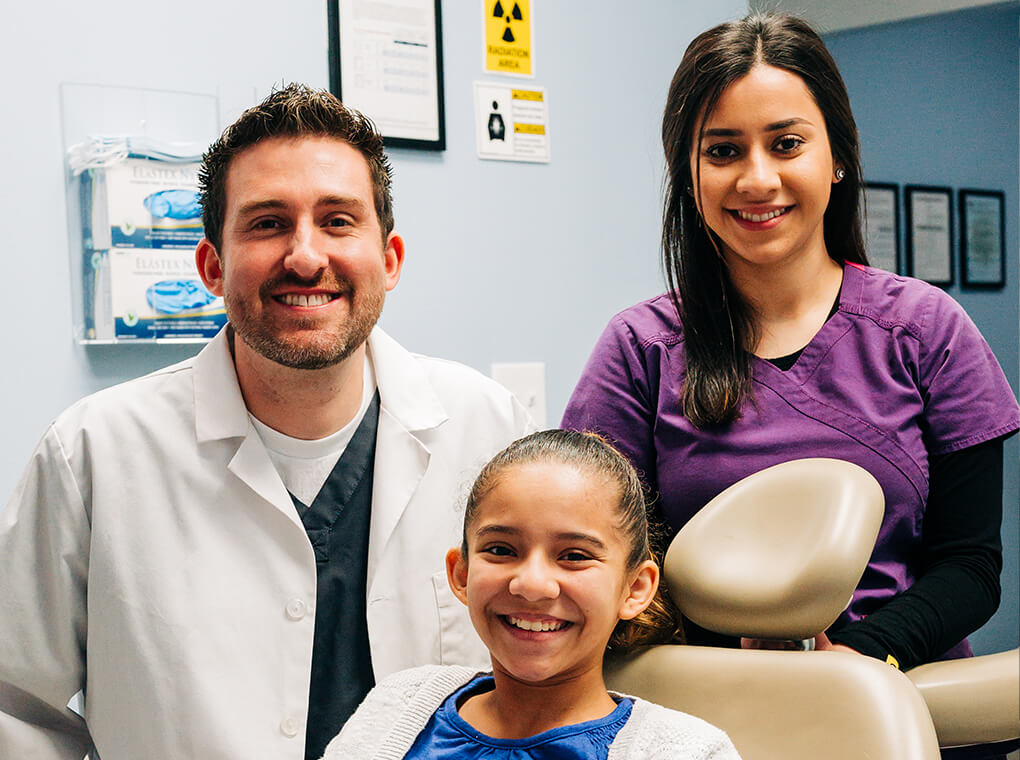 Dentist, hygienist, and happy, smiling female patient.