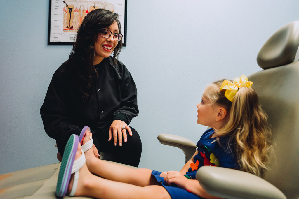 Dentist smiling at a young female patient.