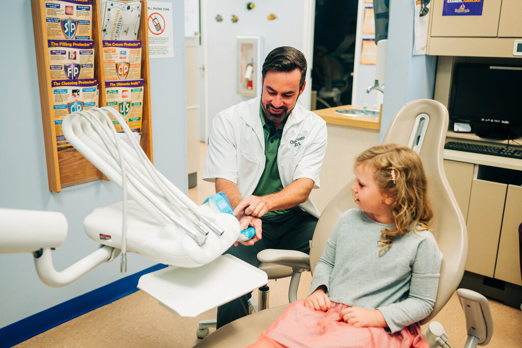 CDP pediatric dentist showing young patient how dental equipment works.