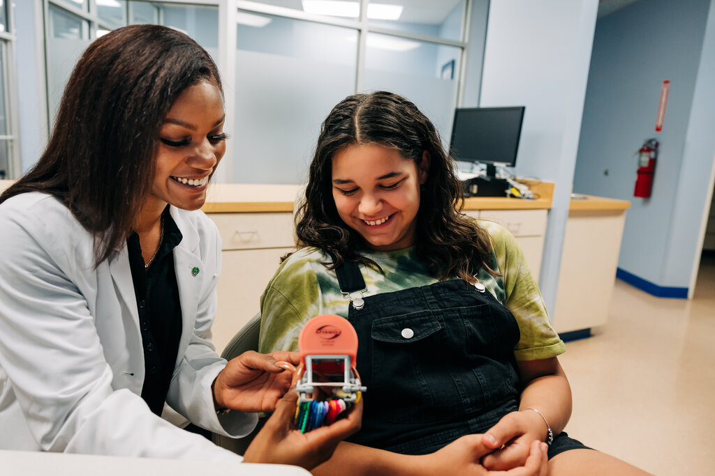 CDP dentist showing teen a fake set of teeth with braces.