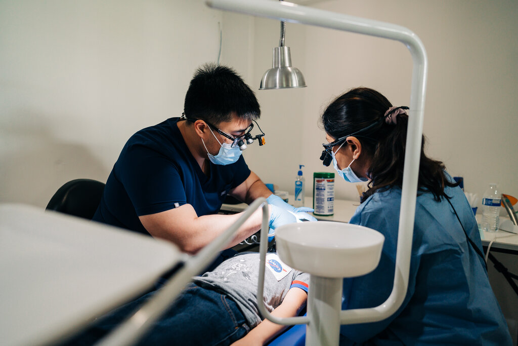Oral Surgeon working on patient as Hygienist assists.