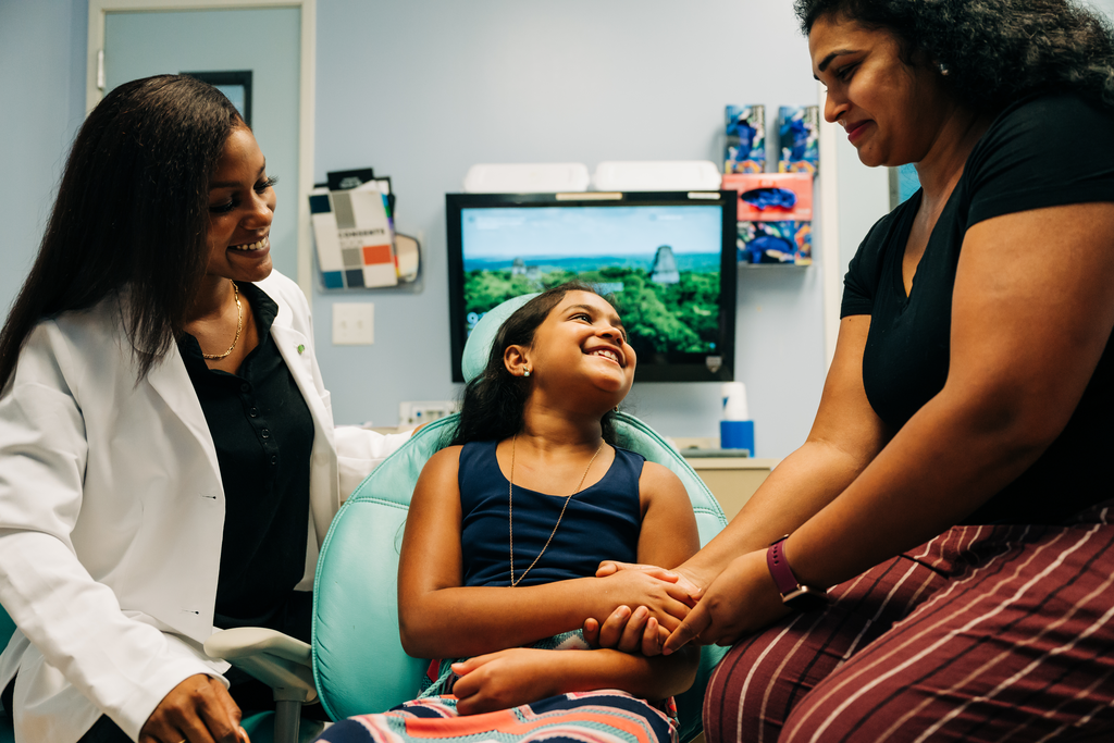 Mother, daughter, female dentist all smiling in the office.