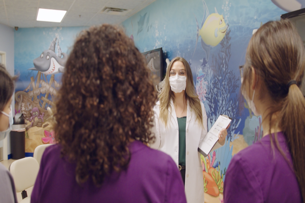 Masked dentist speaking to dental team.