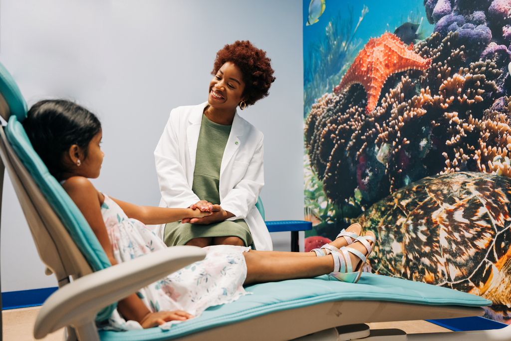 Female dentist smiling at young patient chairside.