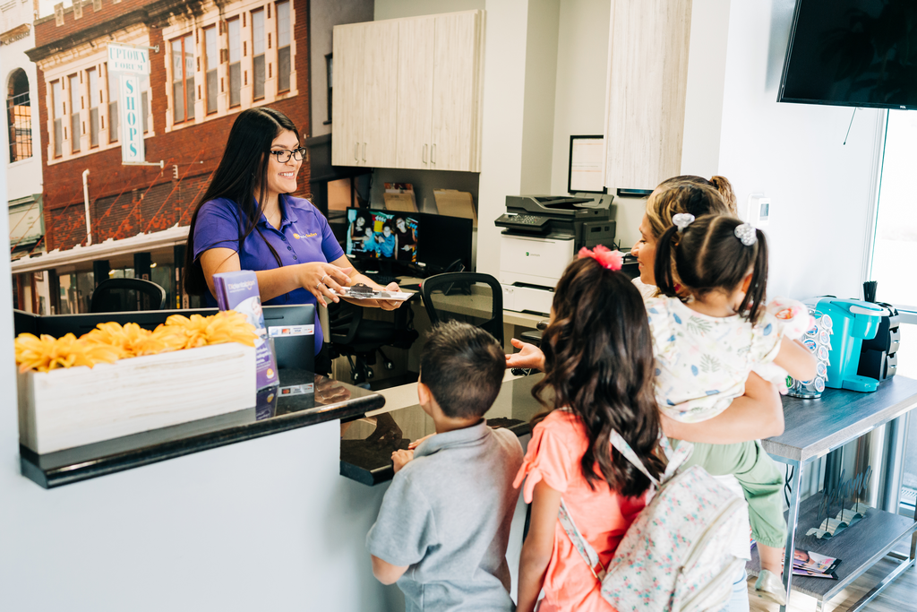 Front desk receptionist checks in a family at the dentist office. Great customer service helps to maintain patient volume.