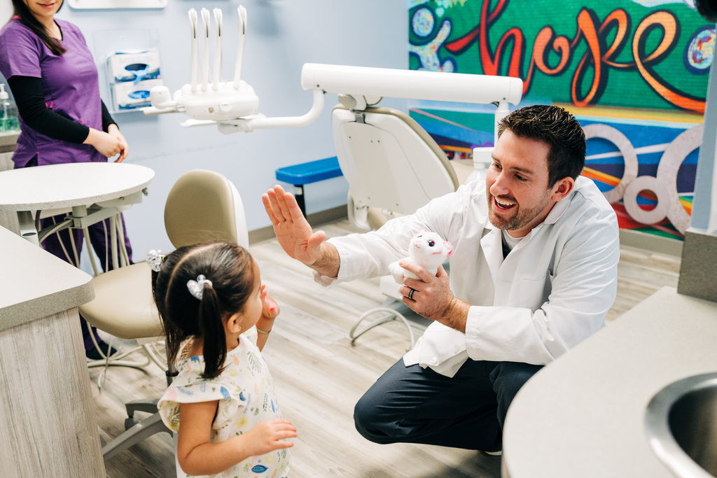 Dentist giving a young patient a high five in a Smile Magic location.